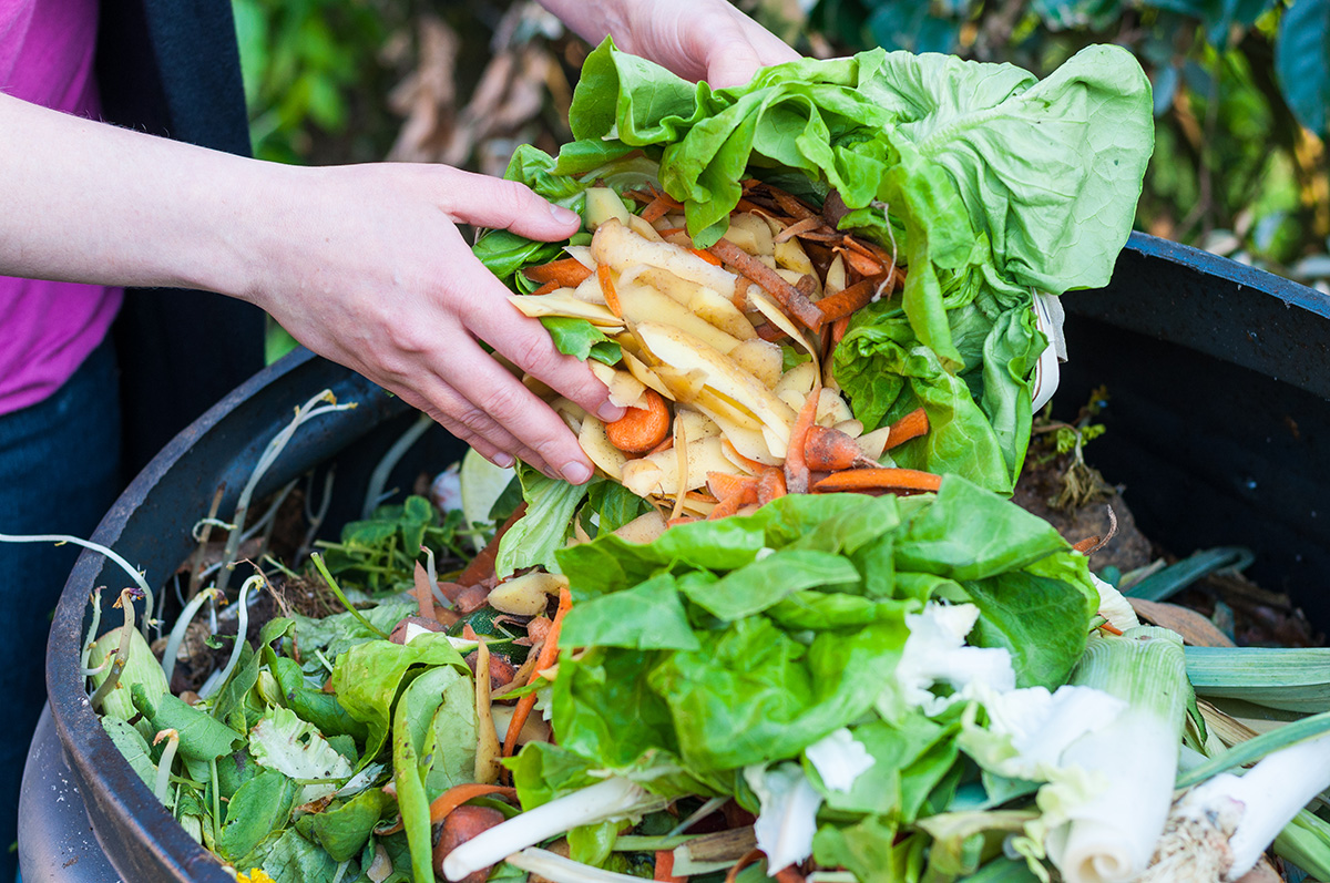 Woman emptying food waste into garden compost bin