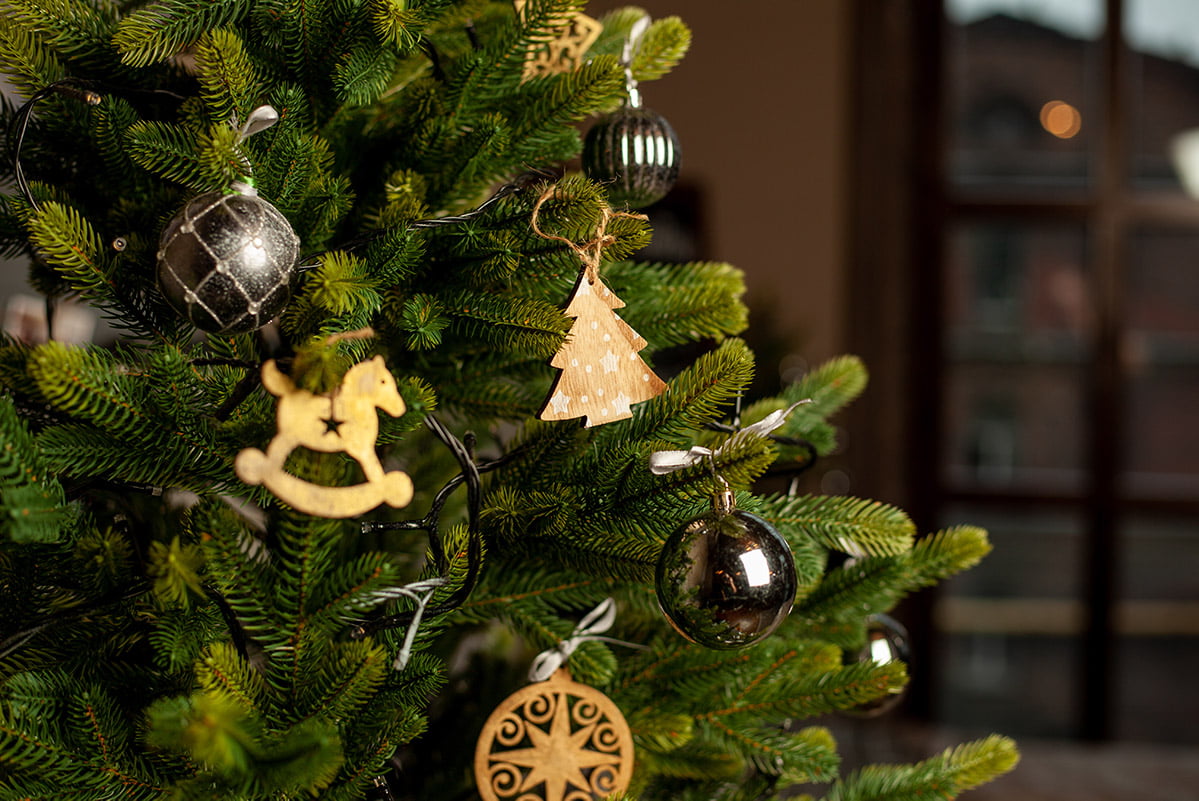 close of decorated Christmas tree with natural, gold and black decorations