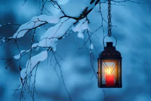candle lantern hanging from snowy branches