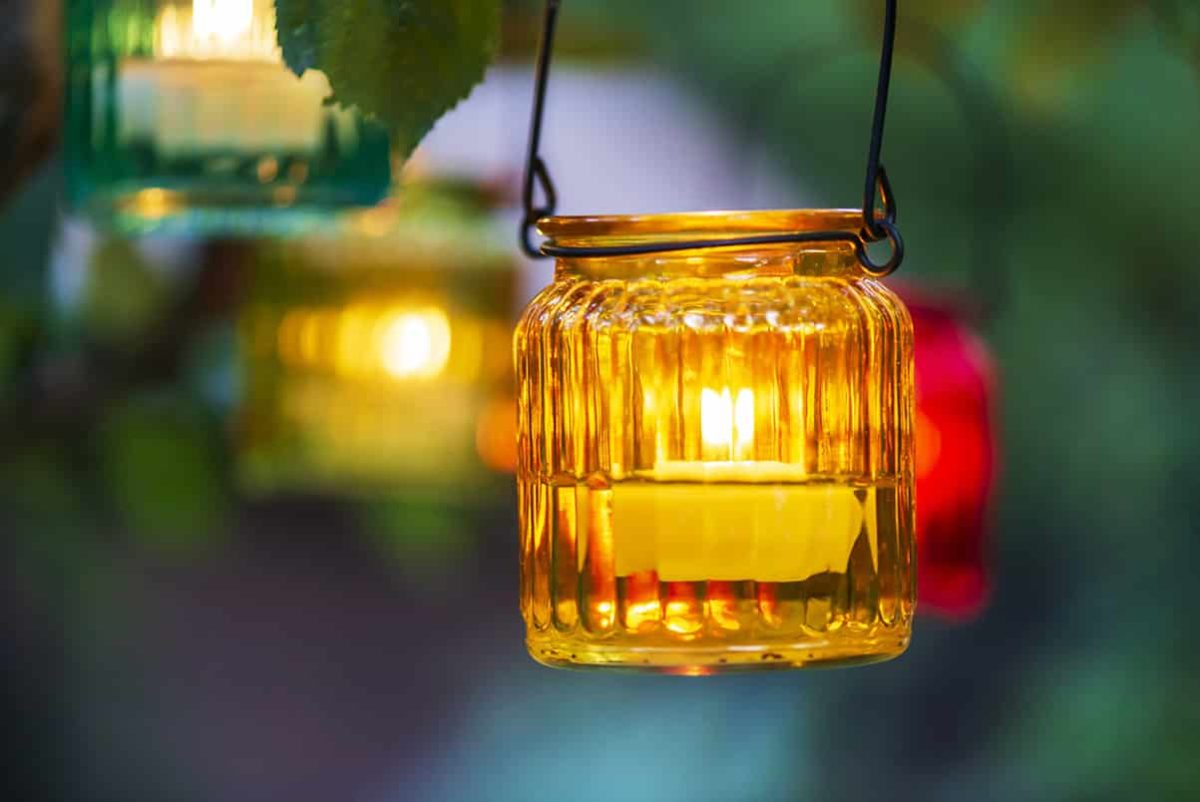 tea light in glass jar hanging from tree