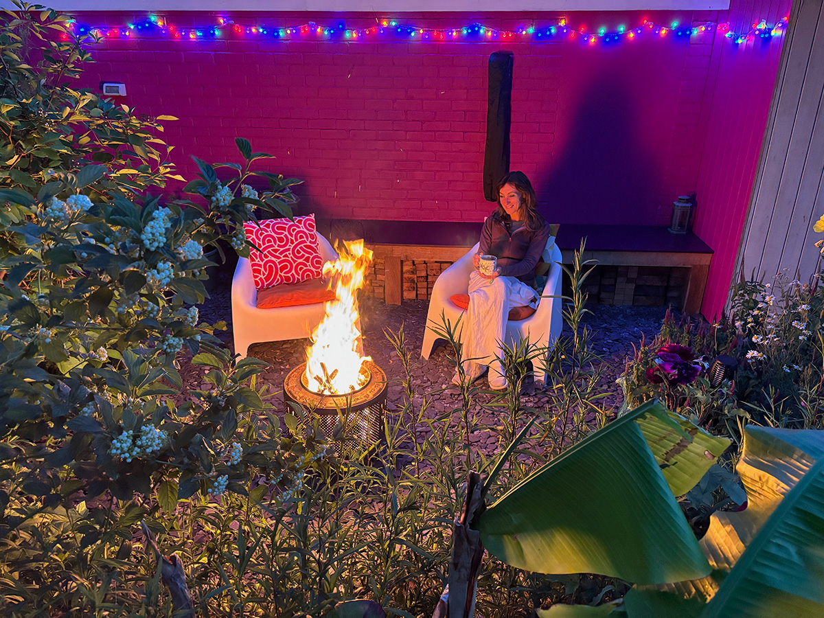 Debi sitting in her garden space around a fire